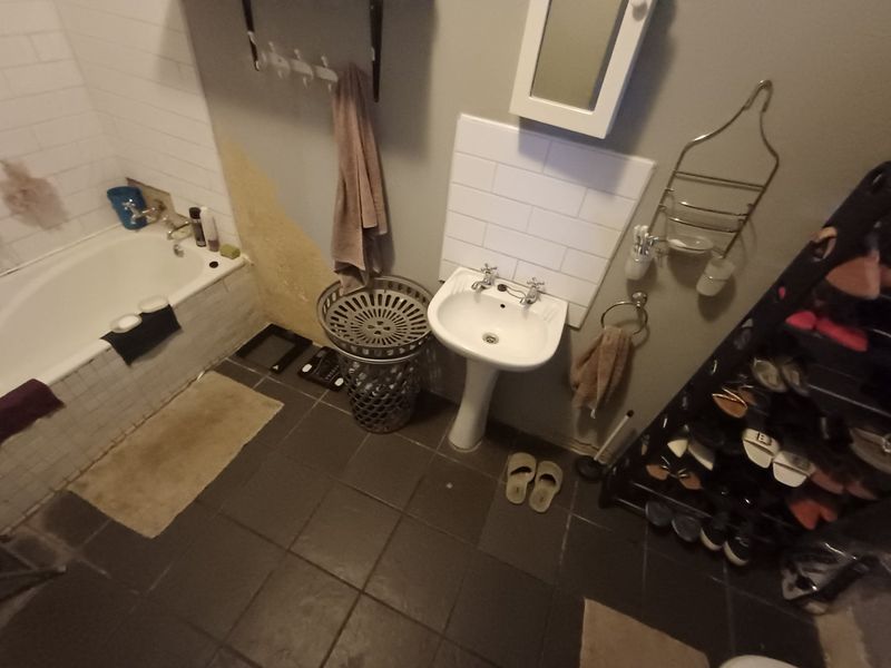A bathroom featuring a bathtub and pedestal basin with subway tile splashbacks, currently requiring wall repairs and cosmetic updates to improve the overall condition.