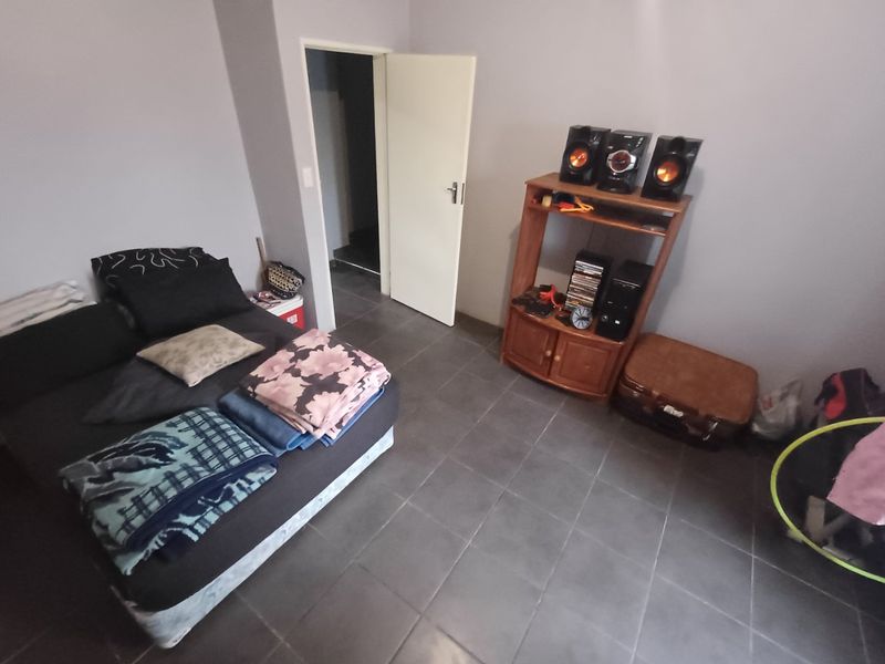 A bedroom featuring dark floor tiles and neutral wall paint, providing a functional space ready for personalization.