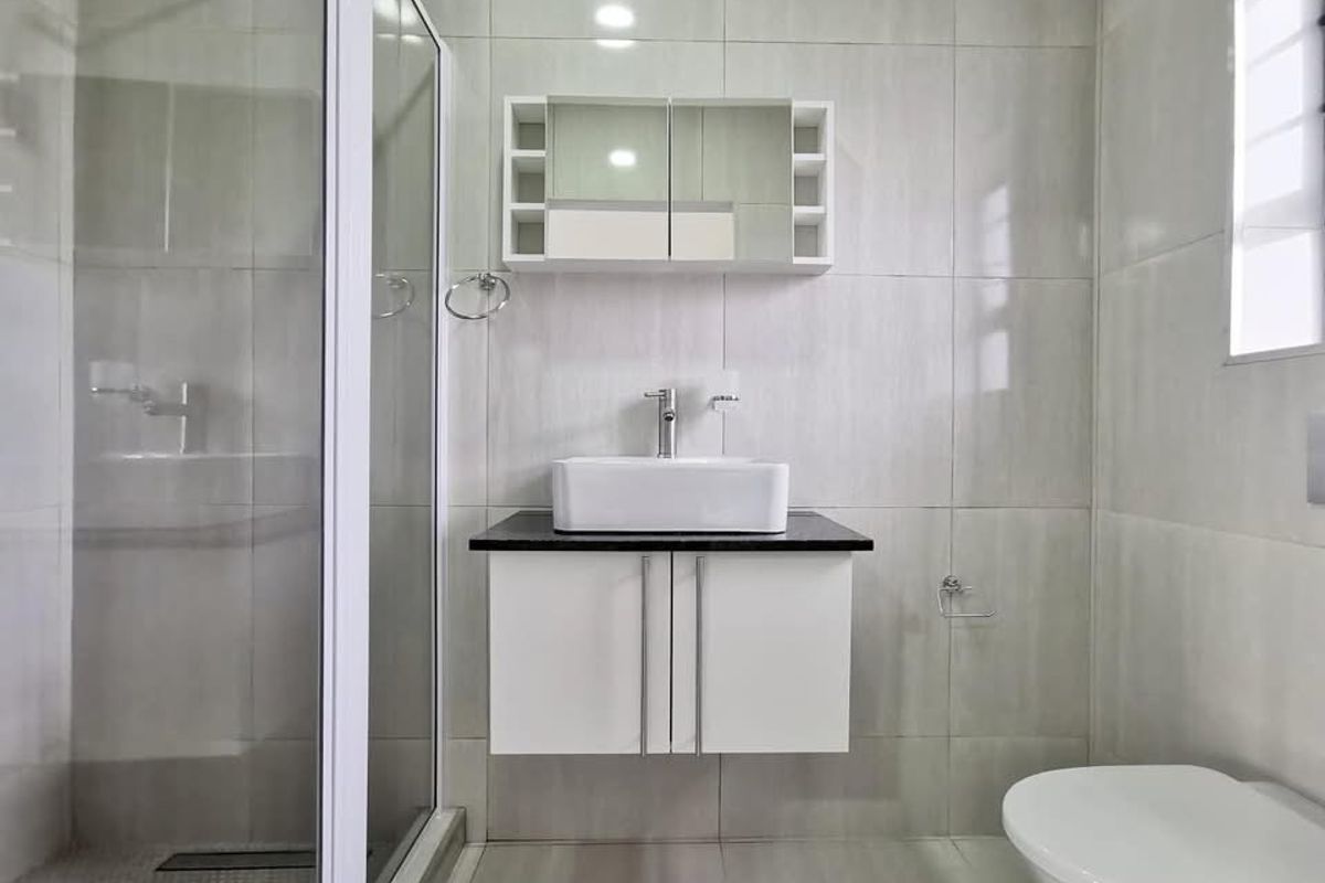 Modern bathroom featuring a floating vanity with a vessel sink, a glass-enclosed shower, and full-height wall tiling.