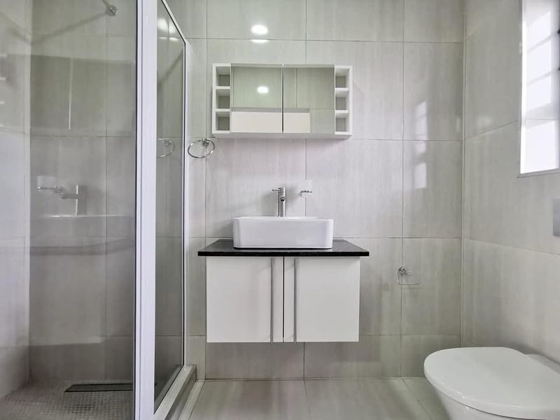 Modern bathroom featuring a floating vanity with a vessel sink, a glass-enclosed shower, and full-height wall tiling.