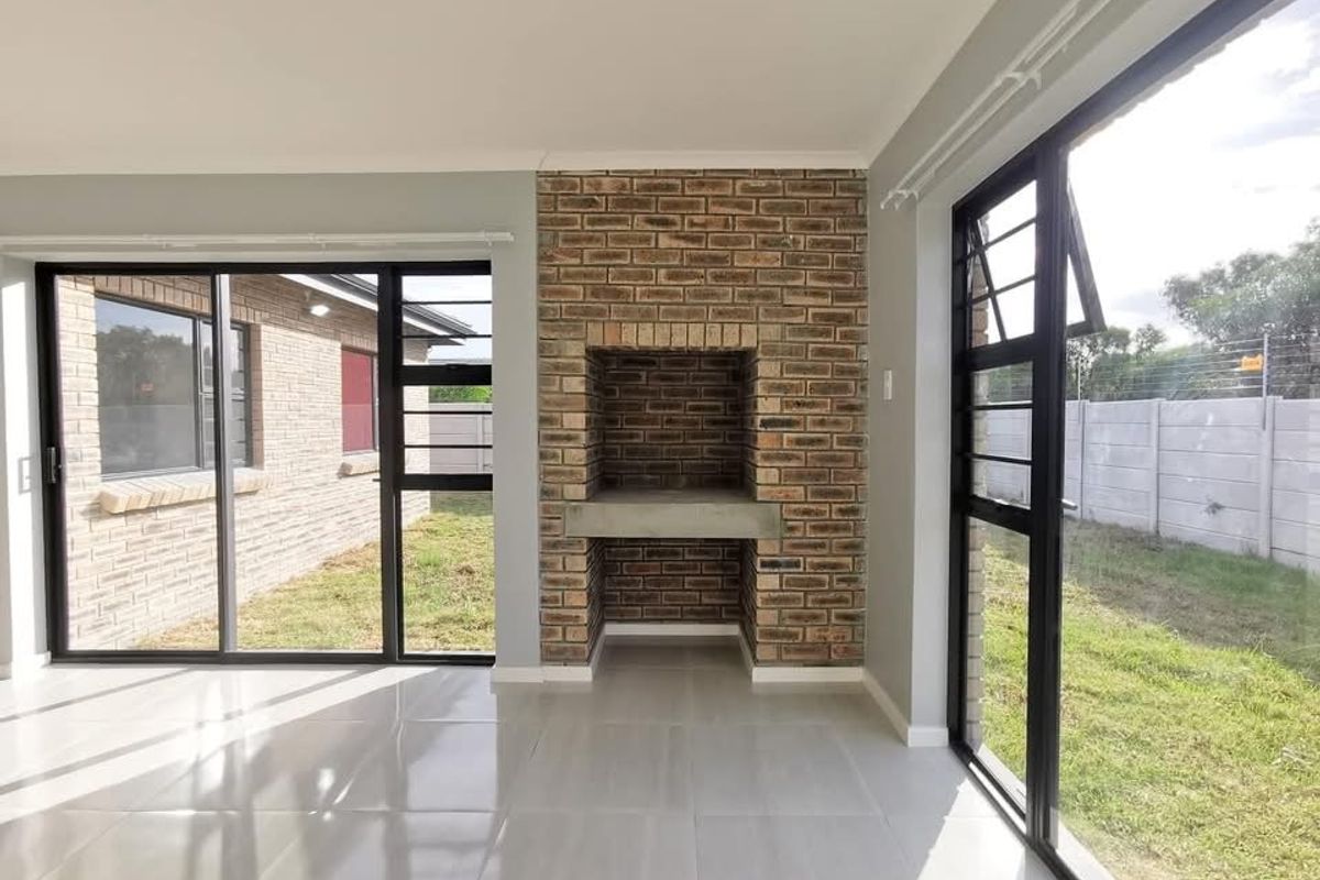 Bright living area featuring a built-in brick fireplace, large sliding glass doors, and modern tiled flooring with direct access to the garden.