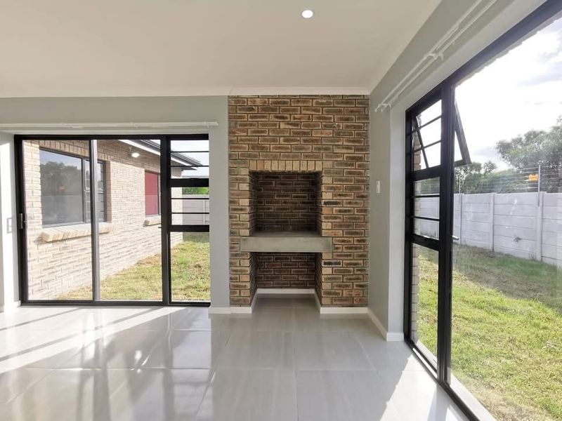 Bright living area featuring a built-in brick fireplace, large sliding glass doors, and modern tiled flooring with direct access to the garden.