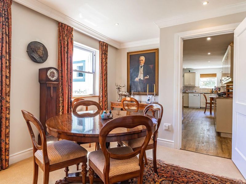 A well-maintained dining room featuring crown molding, recessed lighting, and a clear view into the adjacent kitchen area.