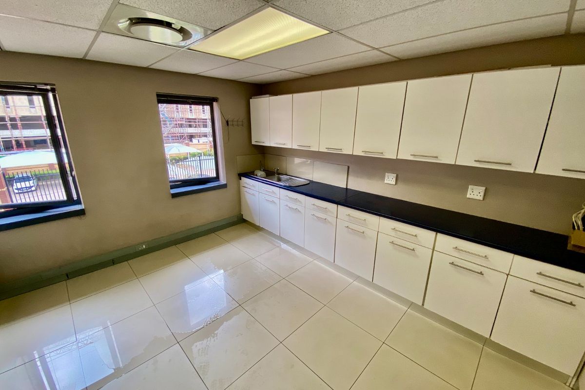 A functional kitchenette featuring white cabinetry, dark countertops, and tiled flooring, currently showing signs of water accumulation on the floor.