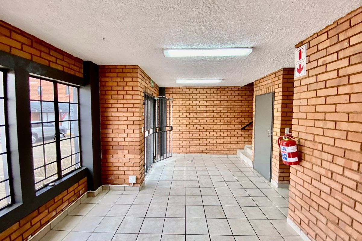 A clean, industrial-style entrance lobby featuring exposed brick walls, tiled flooring, and functional security access points.