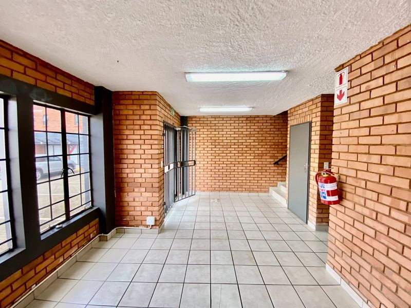 A clean, industrial-style entrance lobby featuring exposed brick walls, tiled flooring, and functional security access points.