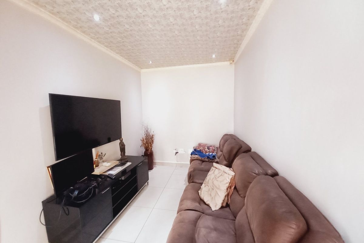 A compact living room featuring tiled flooring, recessed downlighting, and a textured ceiling finish.