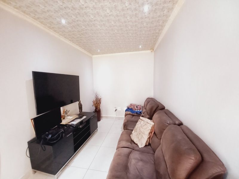 A compact living room featuring tiled flooring, recessed downlighting, and a textured ceiling finish.