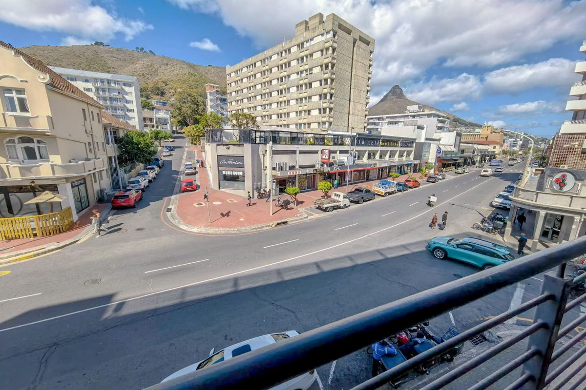 Elevated street view overlooking a busy urban intersection with surrounding apartment buildings and mountain scenery in the distance.