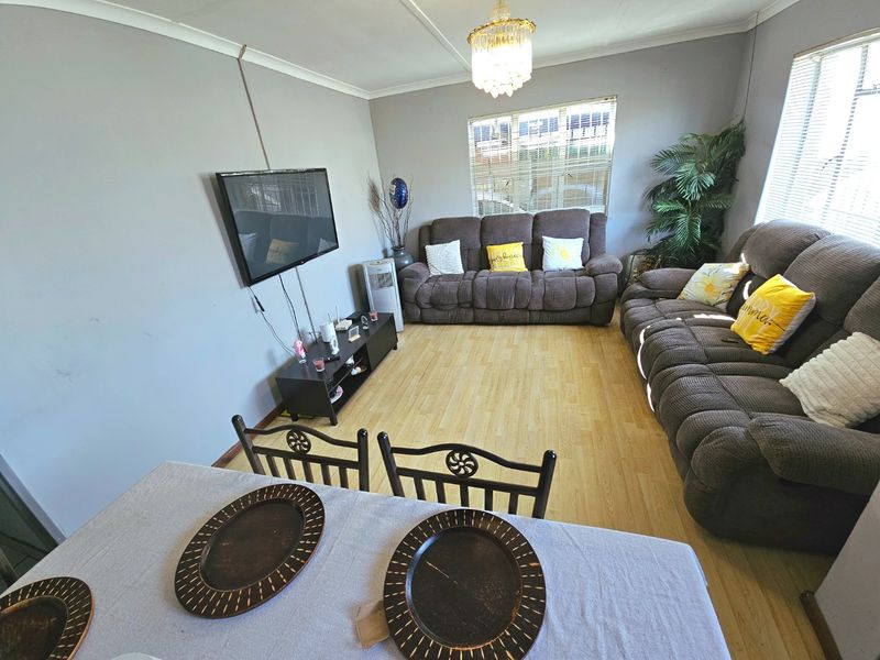 Open plan living and dining area featuring light wood-look flooring, neutral wall tones, and a central chandelier fixture.