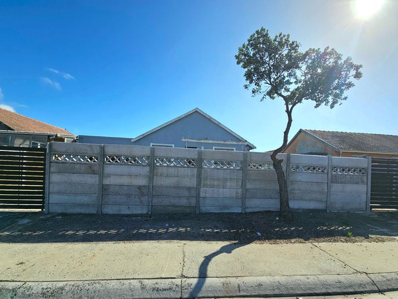 Street view of the property featuring a precast concrete boundary wall and a glimpse of the house roofline.
