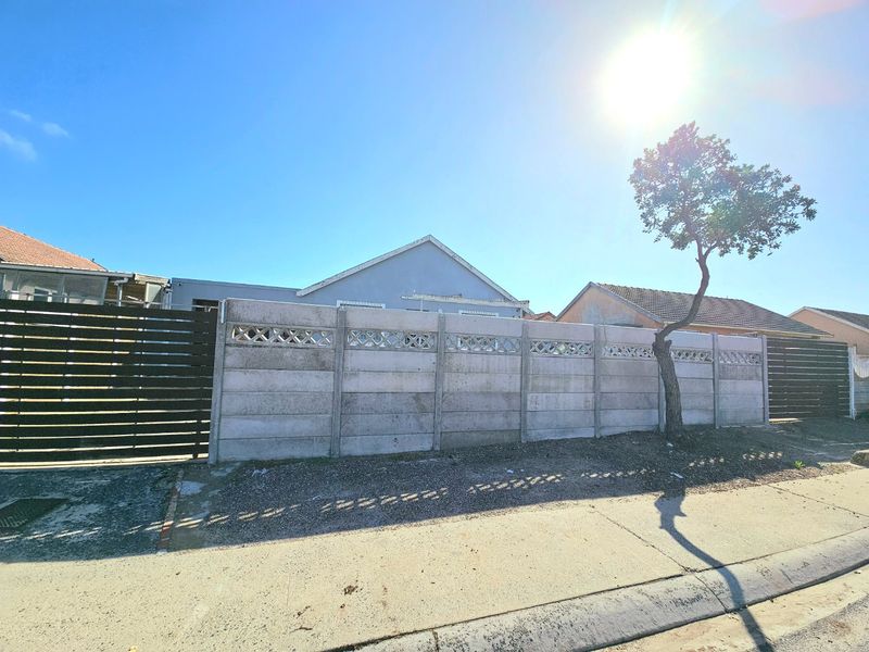 Street view of the property featuring a concrete boundary wall, timber fencing, and a clear view of the house exterior.