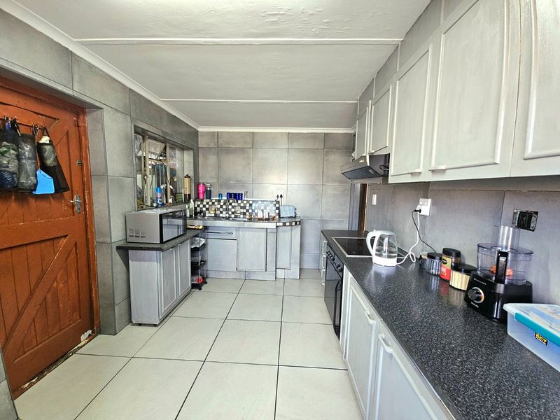 Functional kitchen featuring tiled walls, ample cabinetry, built-in hob, and extractor fan, providing a practical workspace with a neutral aesthetic.