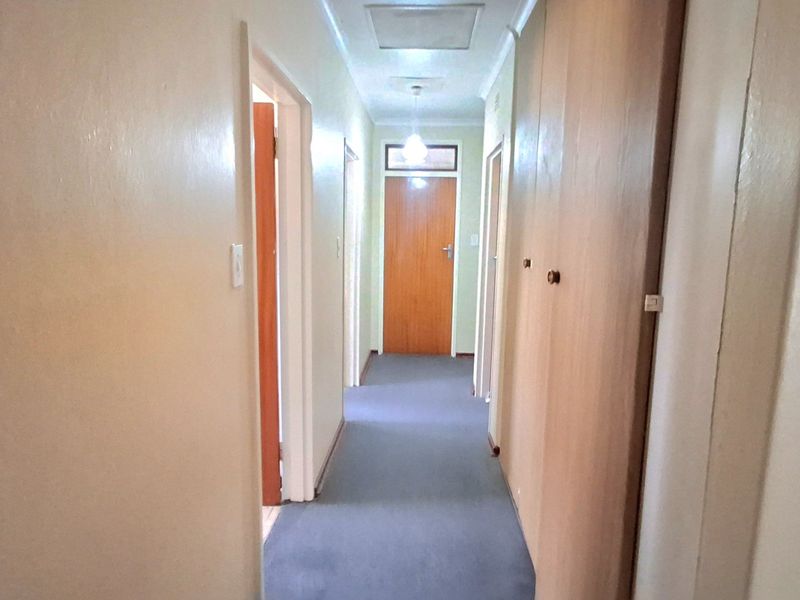 A functional hallway featuring built-in storage cupboards and carpeted flooring, providing access to multiple rooms within the home.