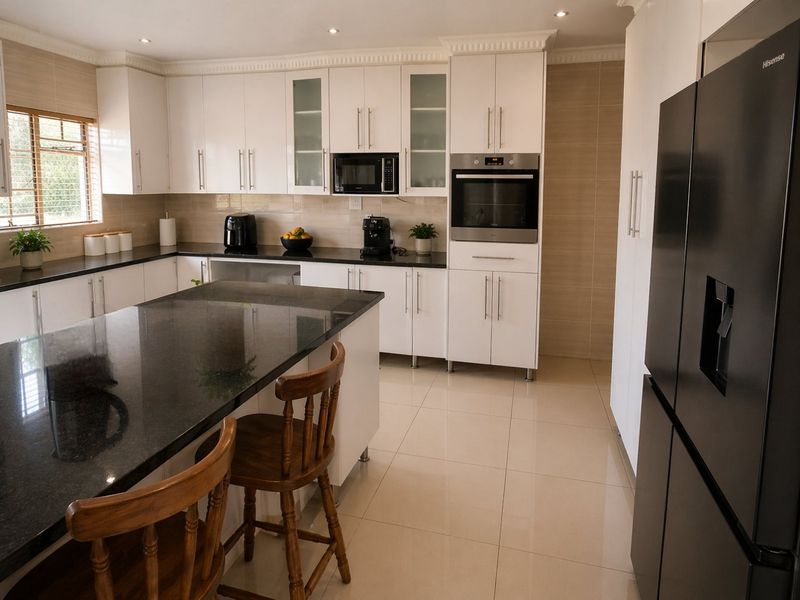 Modern kitchen featuring white cabinetry, dark granite countertops, built-in oven and microwave, tiled backsplash, and polished floor tiles.