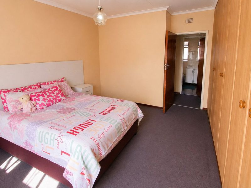 A bedroom featuring built-in wooden cupboards, carpeted flooring, and an en-suite bathroom access.