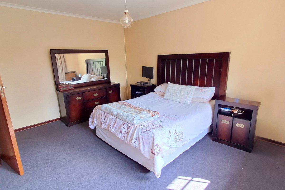 A standard bedroom featuring carpeted flooring, a timber door, and a central pendant light fixture.
