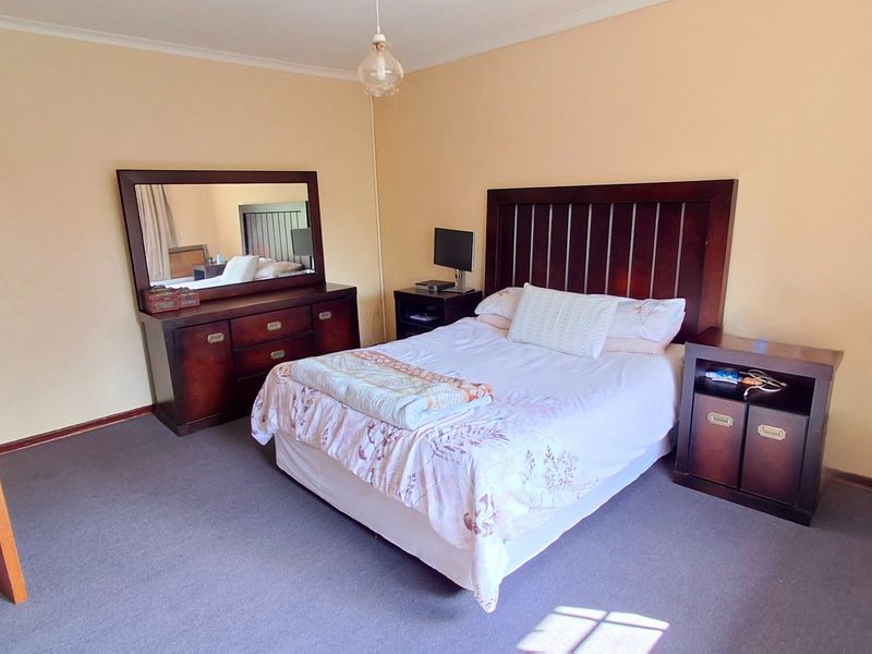 A standard bedroom featuring carpeted flooring, a timber door, and a central pendant light fixture.