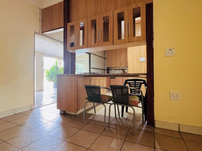A functional kitchen featuring wooden cabinetry, granite countertops, and a convenient pass-through window connecting to the adjacent living area.
