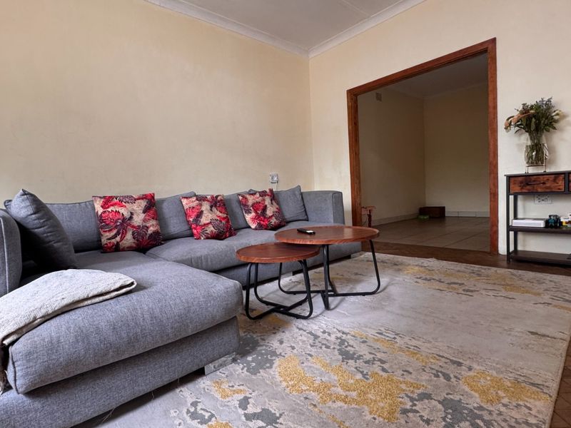 A living room featuring parquet flooring, coved ceilings, and a timber-framed doorway leading to an adjacent space.