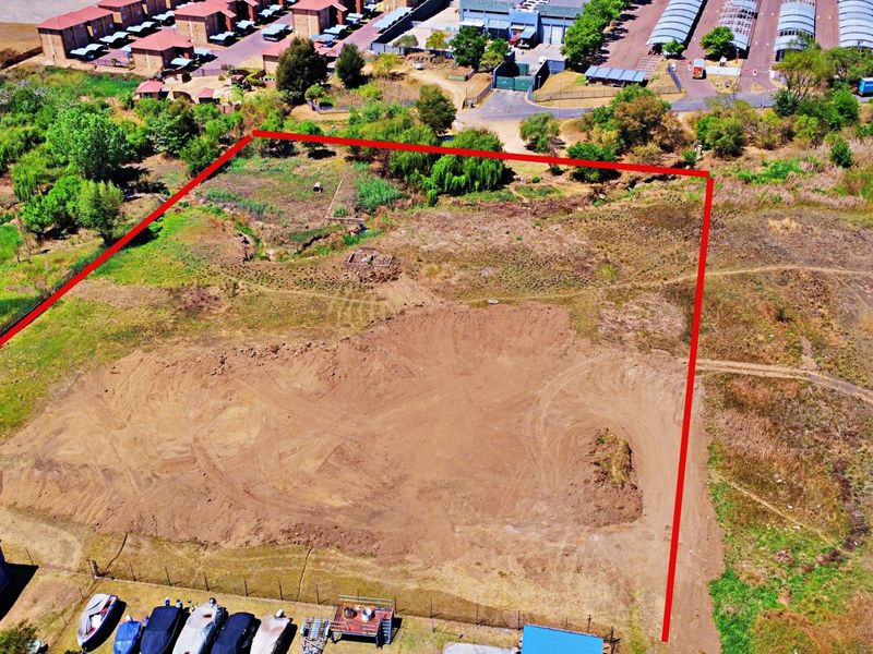 An aerial view of a vacant residential plot with cleared ground, showing the property boundaries and surrounding neighborhood context.