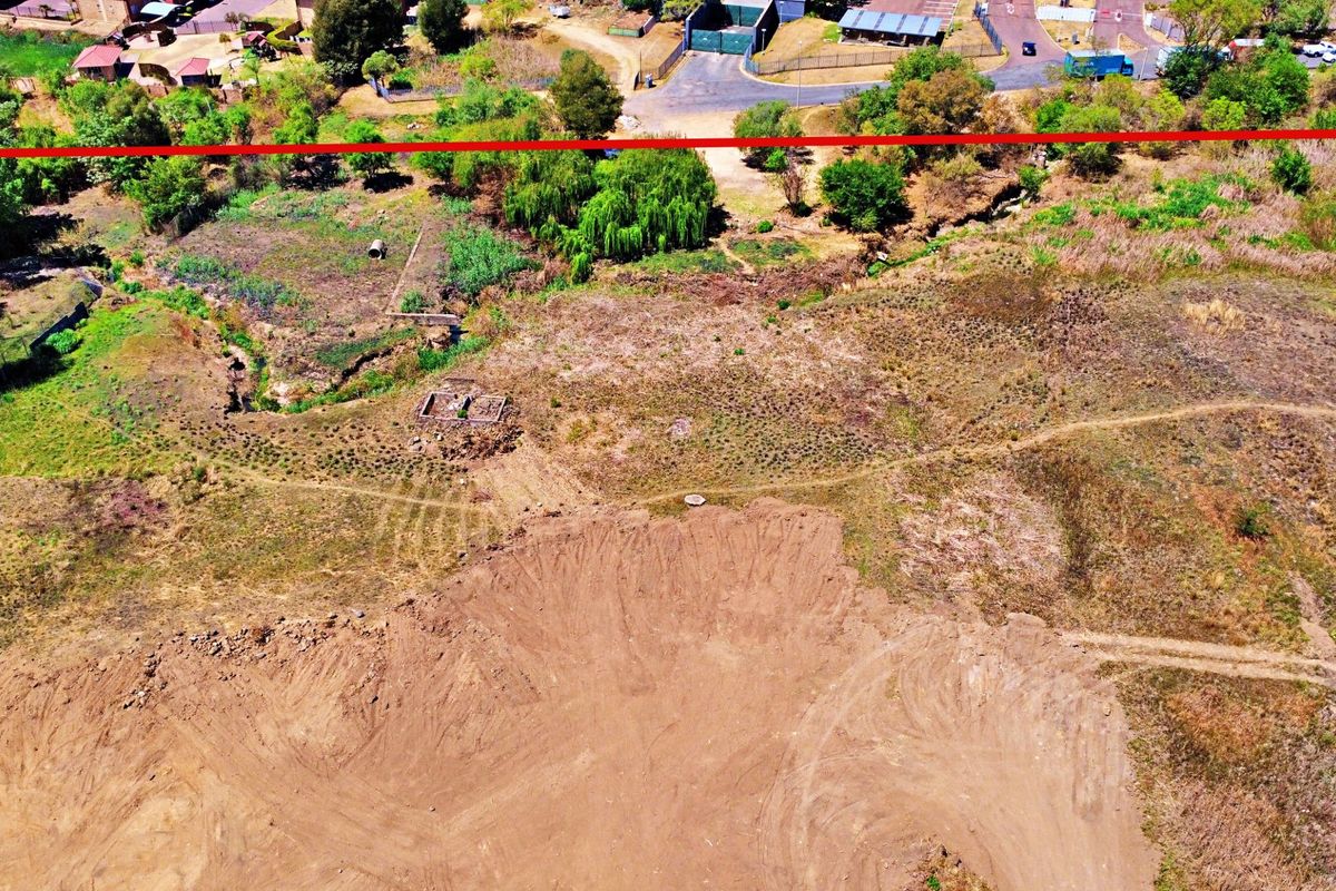 Aerial view of a vacant residential plot featuring cleared earth and natural vegetation, suitable for future development.