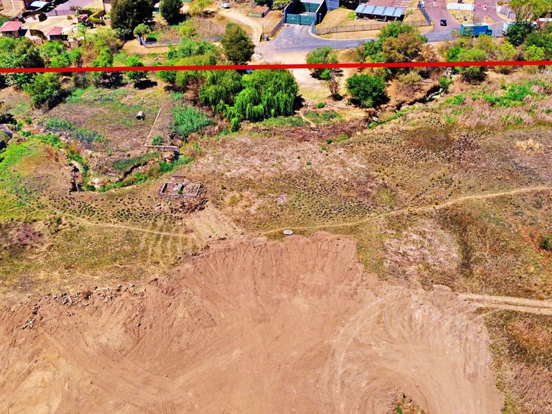 Aerial view of a vacant residential plot featuring cleared earth and natural vegetation, suitable for future development.