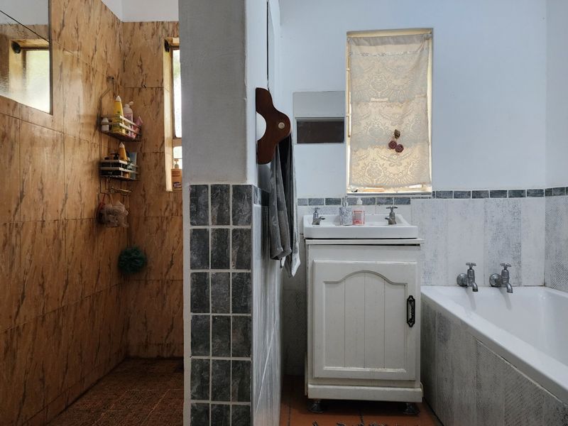 A functional bathroom featuring a built-in vanity, bathtub, and a mix of tiled wall finishes, offering a dated but practical layout.