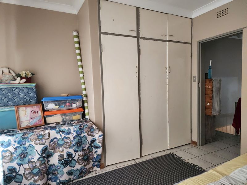 Bedroom featuring built-in cupboards with overhead storage and tiled flooring.