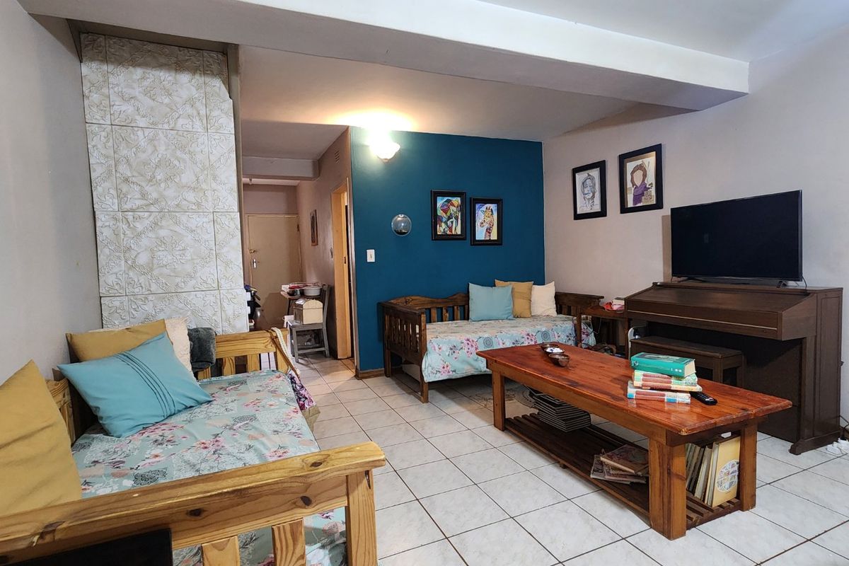 A living room area featuring tiled flooring, a structural beam, and a tiled feature column, offering a functional space with potential for modernization.