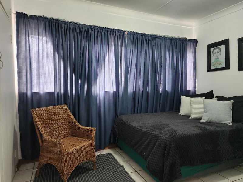 A bedroom featuring tiled flooring and cove cornice detailing, providing a functional space with natural light filtered through window curtains.