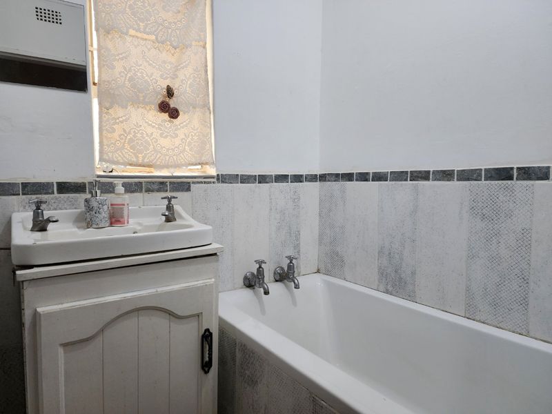 A functional bathroom featuring a vanity cabinet with basin, a bathtub, and tiled wall finishes.