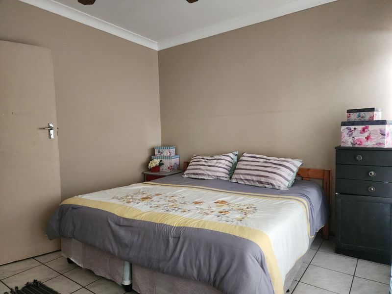 A functional bedroom featuring tiled flooring, a ceiling fan, and neutral wall tones, providing a simple and practical living space.