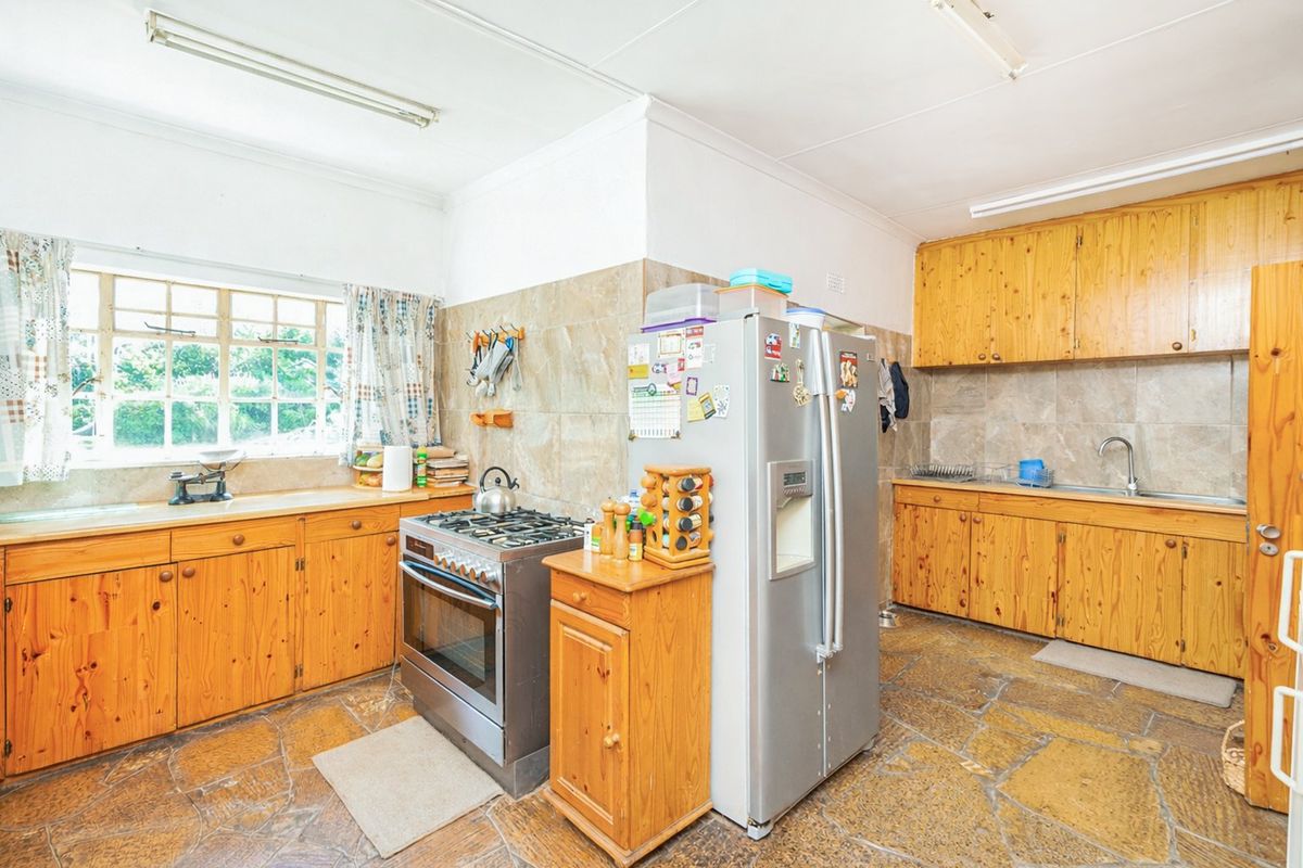 A functional farm-style kitchen featuring pine cabinetry, stone tile flooring, a gas stove, and tiled backsplash, offering a classic rustic aesthetic.