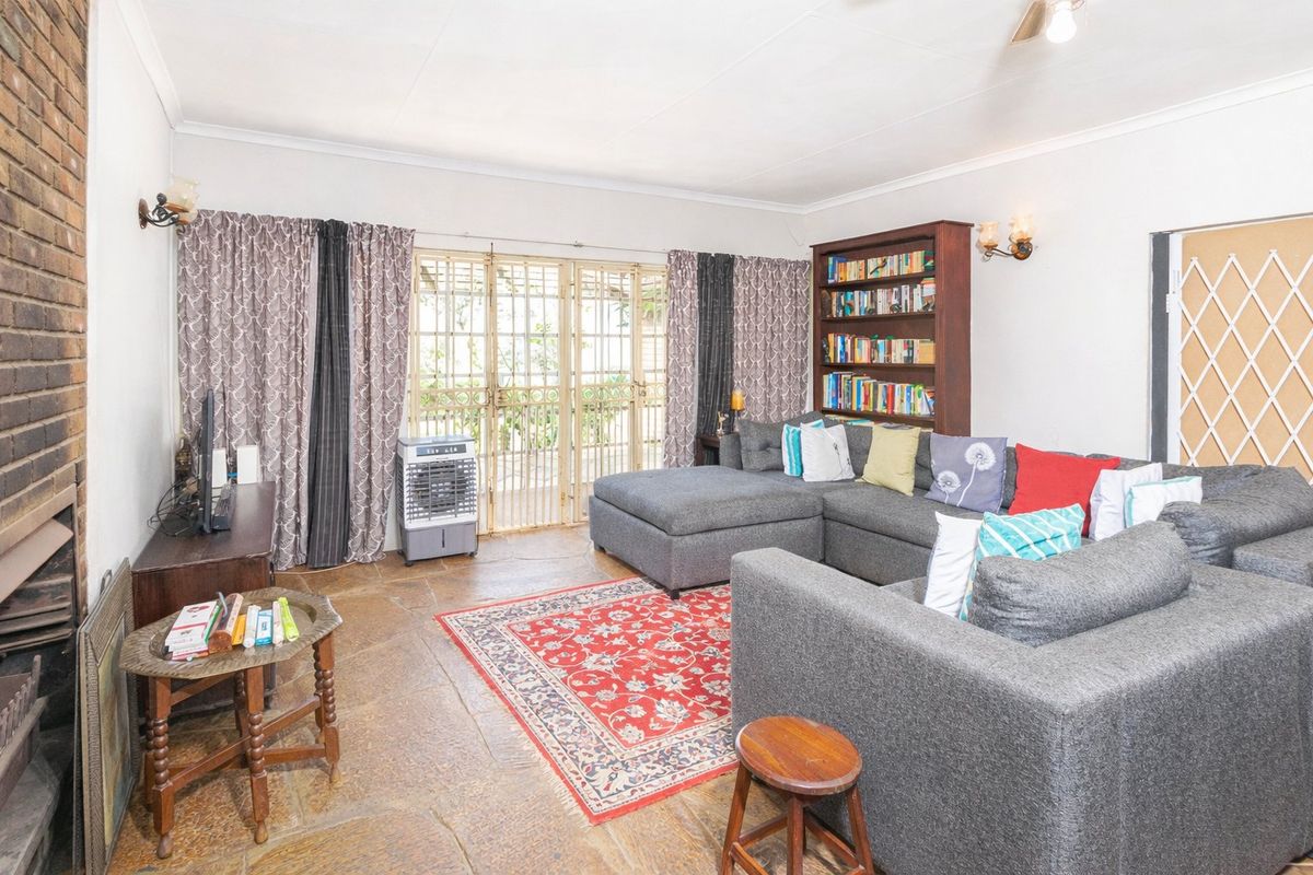 A comfortable living room featuring natural stone flooring, a brick fireplace, and direct access to the outdoor area through a secure sliding door.