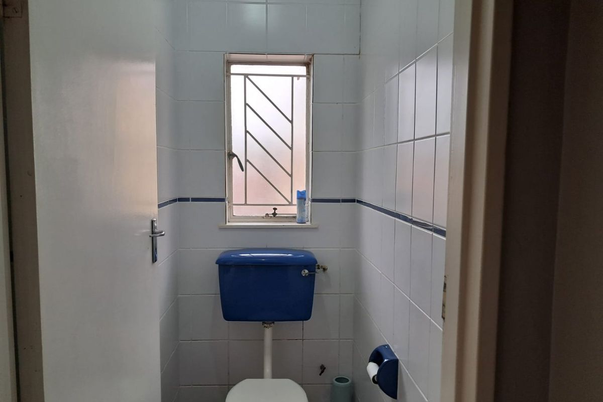 A compact, dated guest toilet featuring white wall tiles with a blue accent border and a blue cistern.