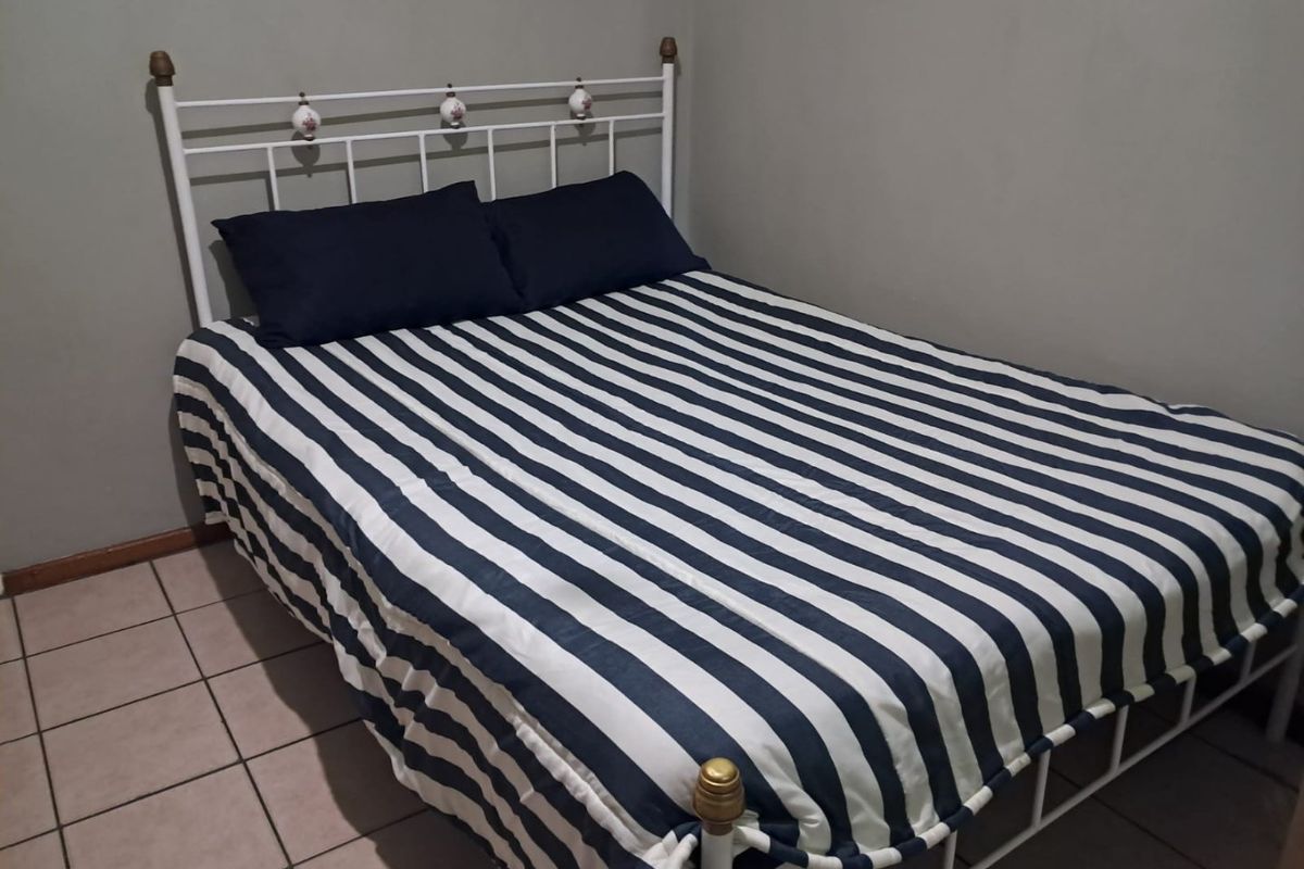 A simple bedroom featuring tiled flooring and neutral wall finishes.