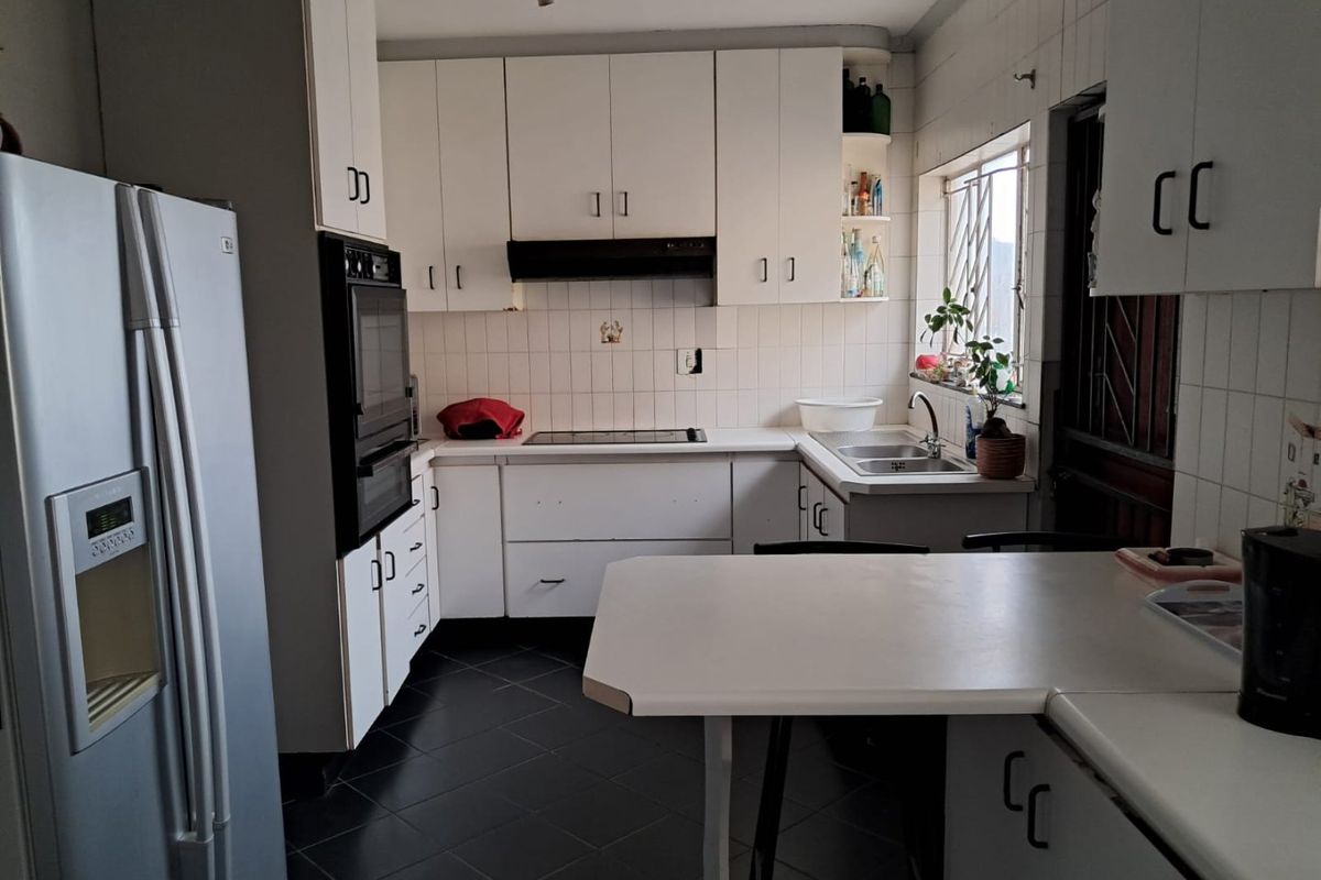A functional kitchen featuring white cabinetry, a built-in oven, a cooktop with an extractor fan, and a double sink with tiled splashbacks.