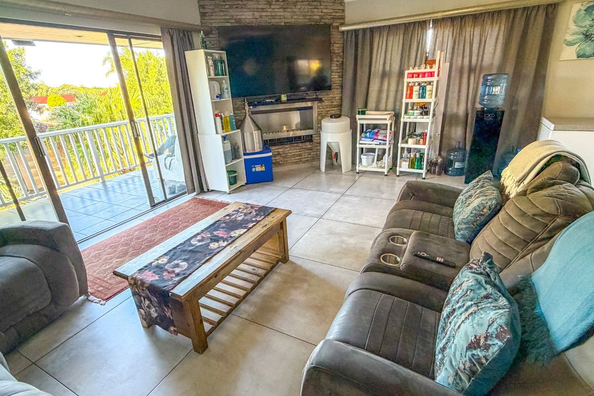 Spacious living room featuring large format floor tiles, a stone-clad feature wall with a built-in fireplace, and direct access to an outdoor balcony.