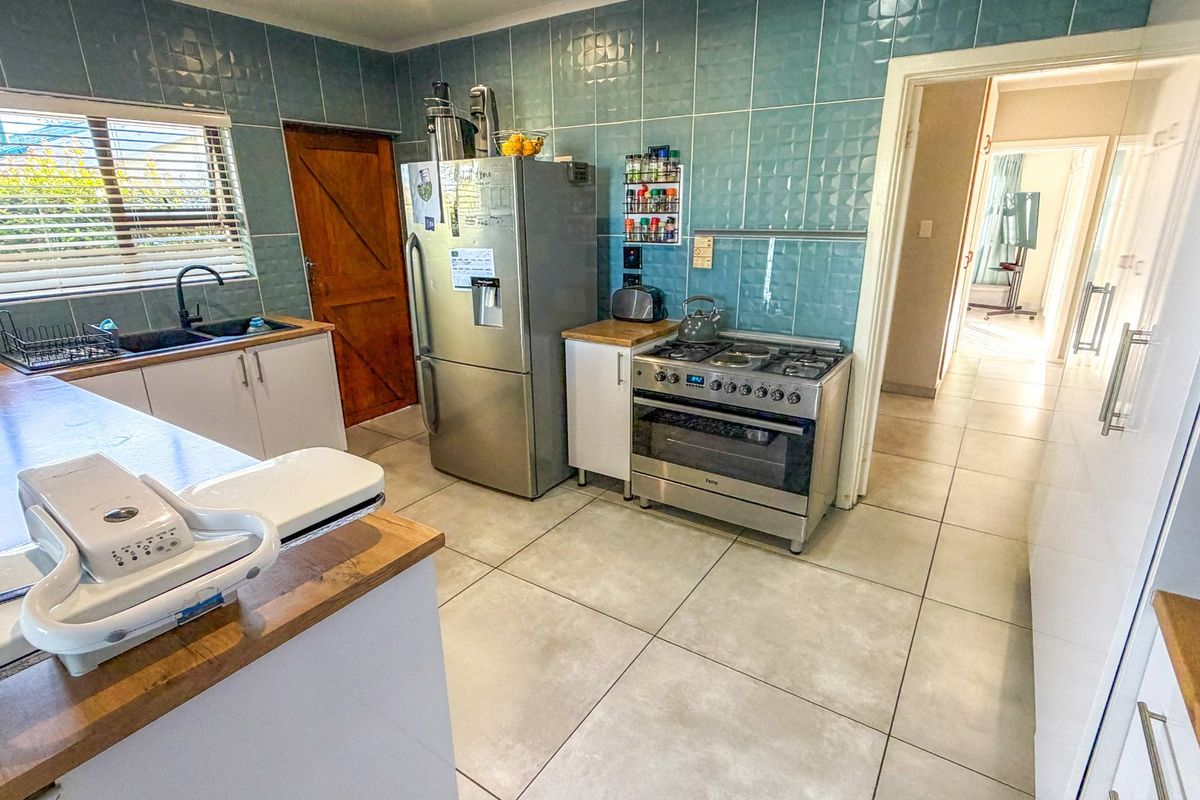 A functional kitchen featuring tiled splashbacks, wooden countertops, a gas stove with oven, and tiled flooring, providing a practical workspace.