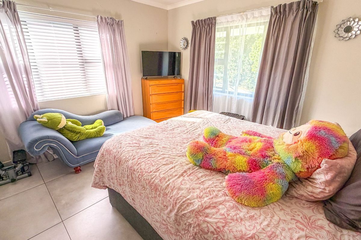 A bedroom featuring tiled flooring and dual windows with curtain rails, providing natural light and a functional layout.