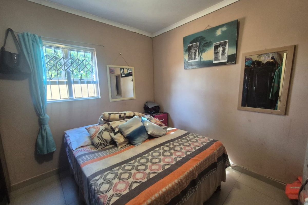 A standard bedroom featuring tiled flooring, neutral wall finishes, and a window fitted with security bars.