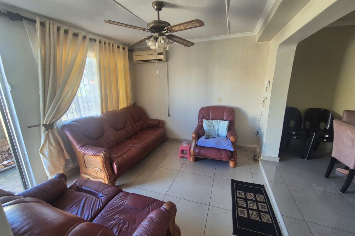 A living room featuring tiled flooring, a ceiling fan, and a wall-mounted air conditioning unit, with access to an outdoor area via a sliding door.