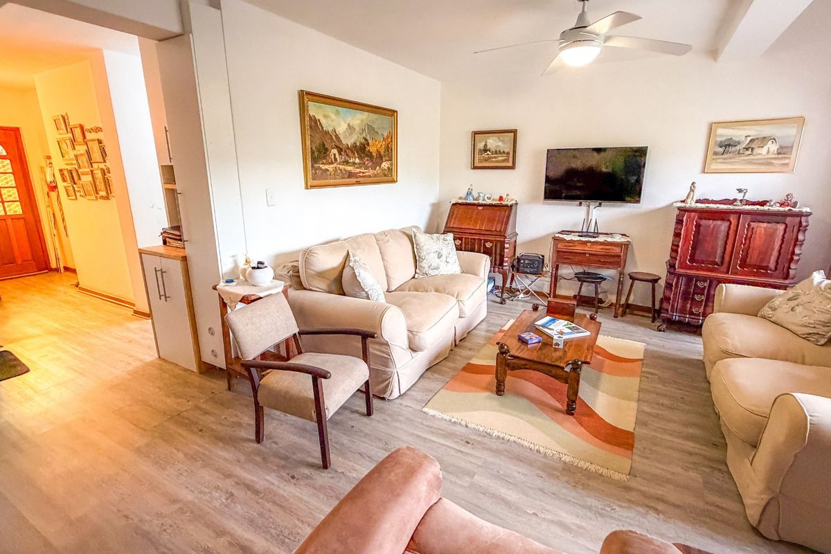 A comfortable living room featuring light-toned laminate flooring, a ceiling fan, and neutral wall finishes, providing a functional and inviting space.