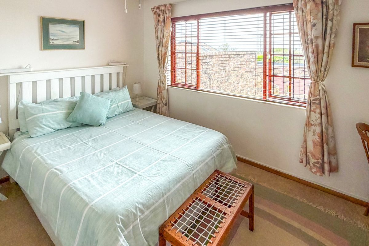 A well-lit bedroom featuring carpeted flooring and a large window, providing a comfortable and functional living space.
