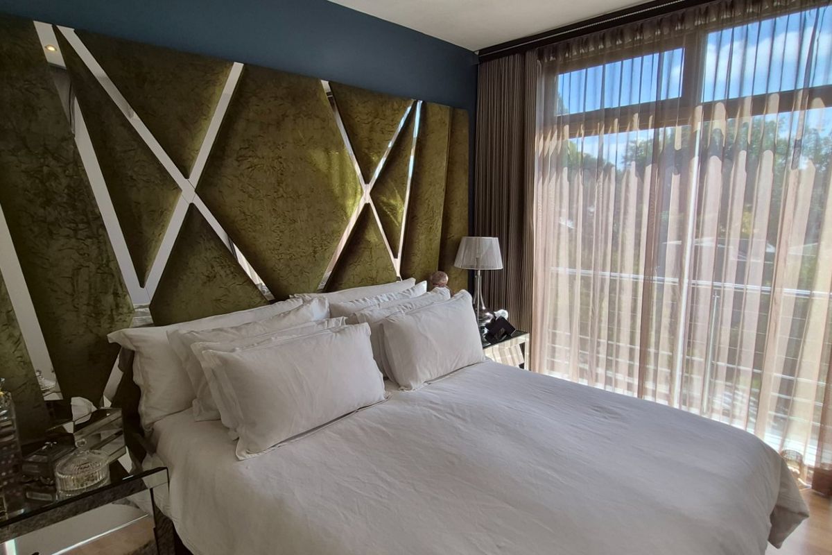 A well-appointed bedroom featuring large floor-to-ceiling windows with integrated curtain tracks, providing ample natural light and access to an adjoining balcony.