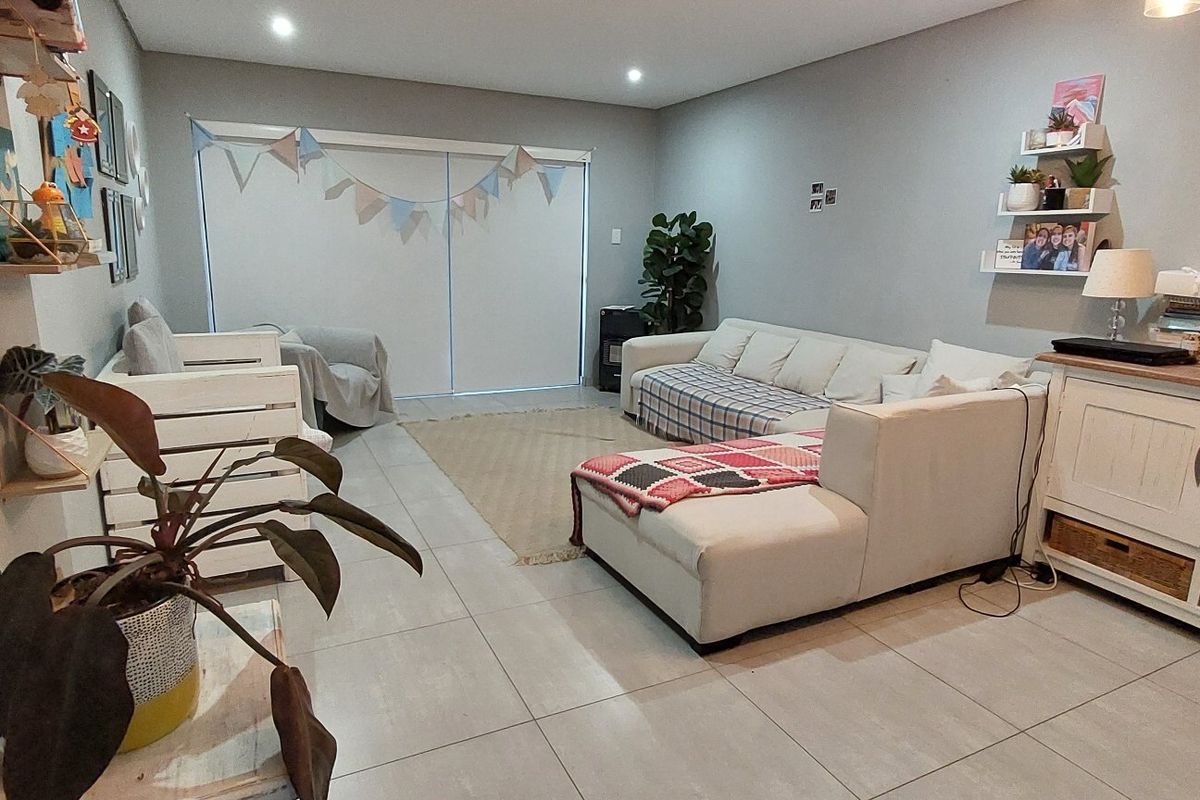 A spacious living room featuring neutral tiled flooring, recessed downlighting, and a large sliding glass door providing access to the exterior.