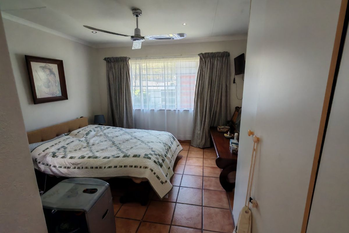 A bedroom featuring tiled flooring, a ceiling fan, and built-in storage, offering a functional space with natural light from the window.