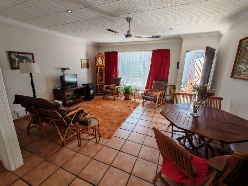 Open plan living and dining area featuring tiled flooring, a ceiling fan, and textured ceiling tiles with direct access to an outdoor space.