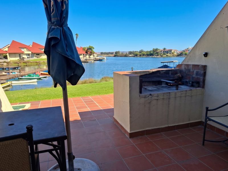 Covered patio area featuring a built-in braai, tiled flooring, and direct views over the waterfront.